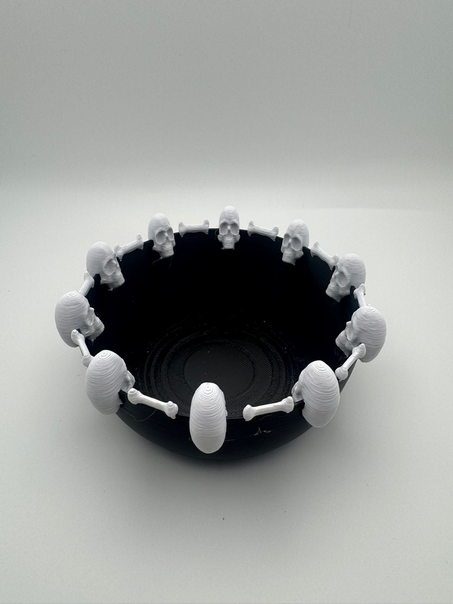 Black bowl with white skull-shaped handles on a white background
