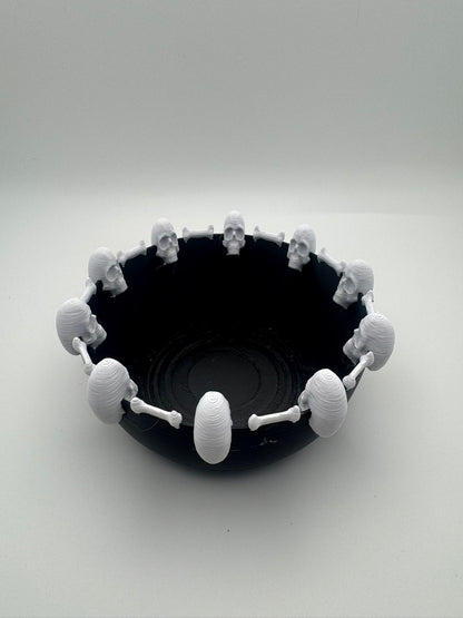 Black bowl with white skull-shaped handles on a white background